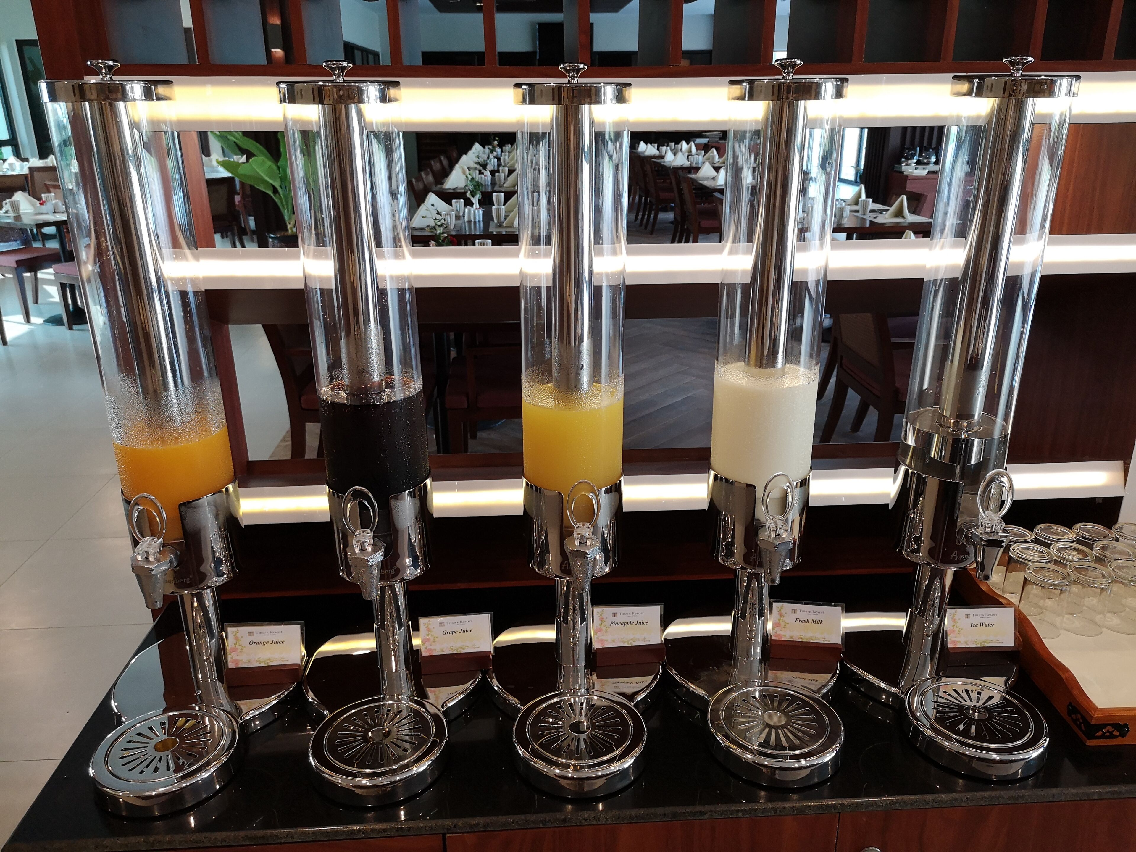 A bar area with multiple juice dispensers labeled with different types of juices.