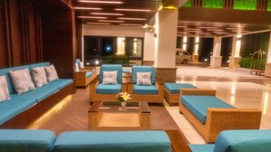 A lobby with blue sofas and wicker furniture, a coffee table with a vase, and a view of a parking area. - Tmark Resort Vang Vieng (Vang Vieng)
