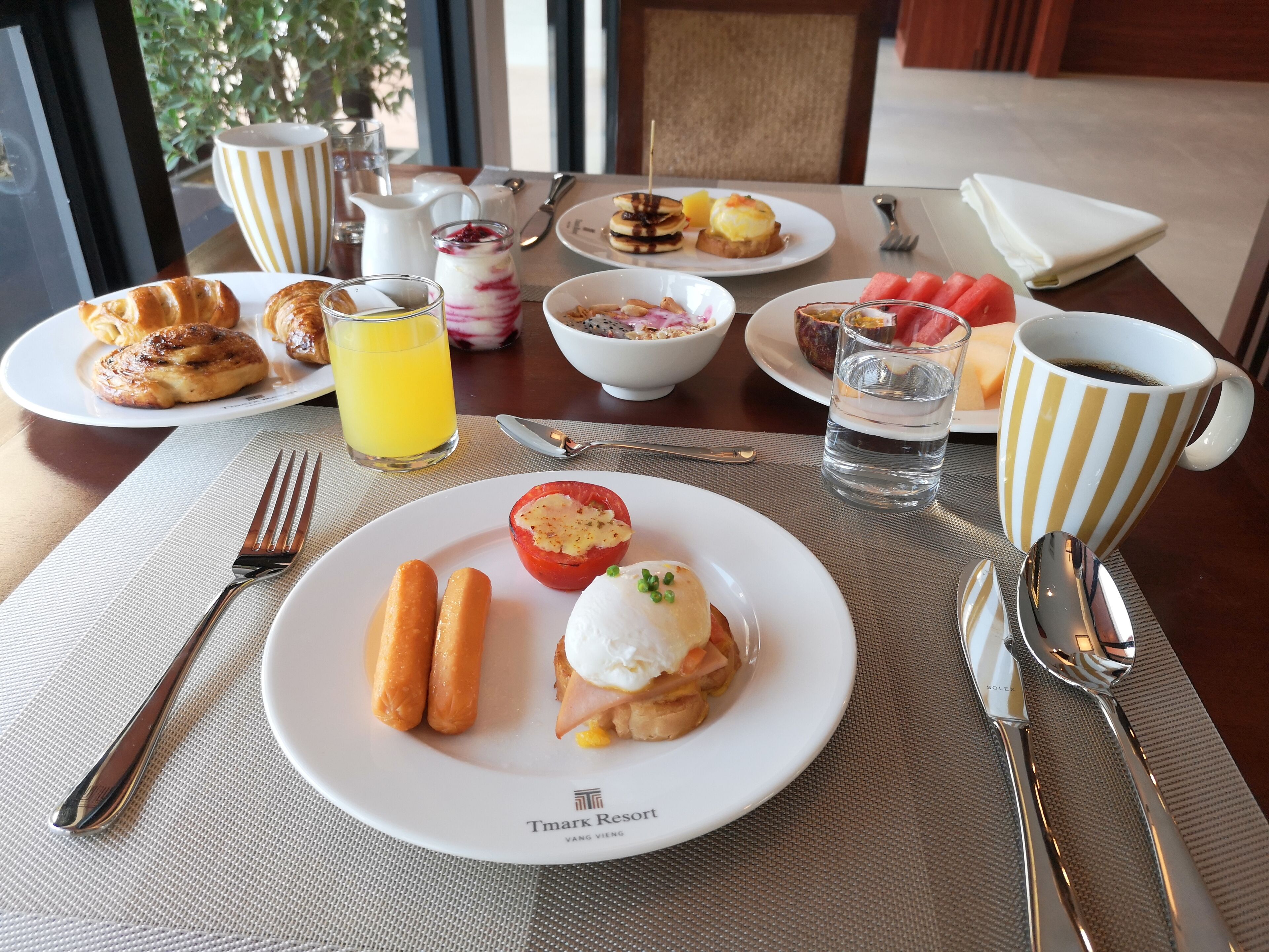 A breakfast table with plates of food, a glass of orange juice, and a cup of coffee.