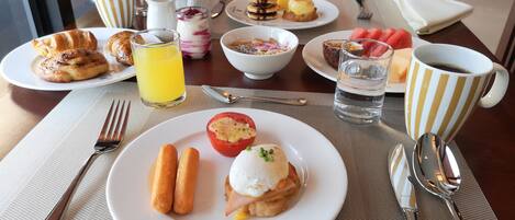 A breakfast table with plates of food, a glass of orange juice, and a cup of coffee.