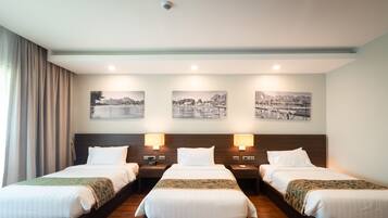 A hotel room with two beds, a headboard, and three wall-mounted picture frames.