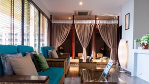 A modern living room with wicker furniture, a teal sofa, and a large window with curtains. - Tmark Resort Vang Vieng (Vang Vieng)