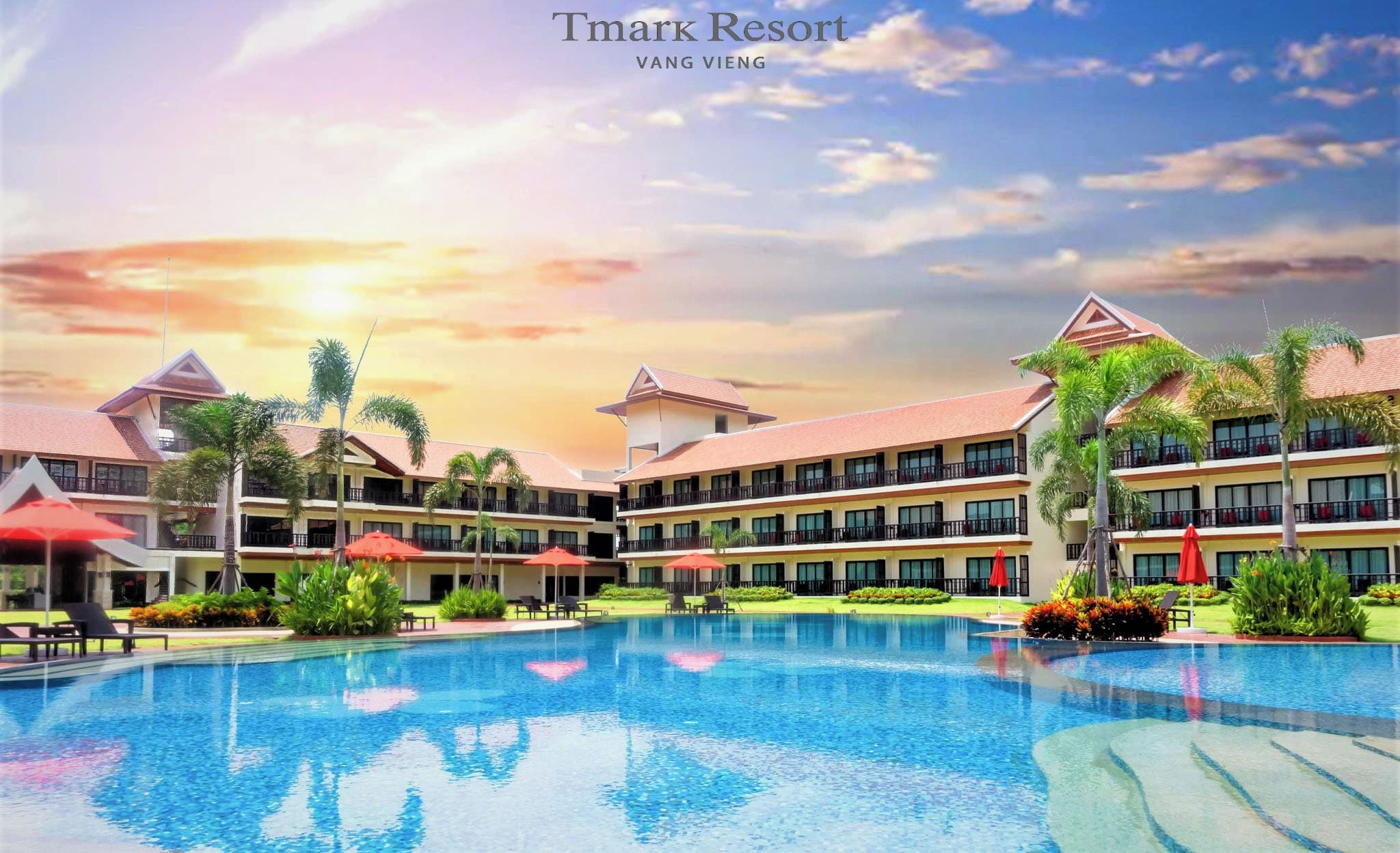 A resort with a swimming pool, multiple buildings, and palm trees.