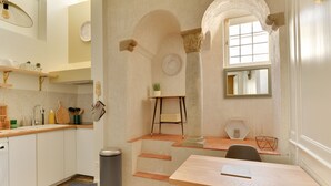 Una cocina compacta con armarios blancos, encimera de madera, una pequeña mesa y una ventana con vistas.