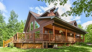 A log cabin with a large porch and a satellite dish.