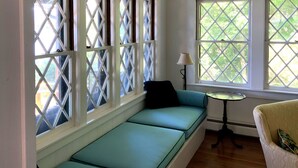 Ein Zimmer mit einer fest eingebauten Sitzbank entlang eines Fensters mit Rautenmusterglas.