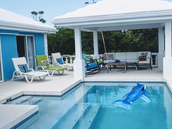 A pool area with lounge chairs and a covered seating area.