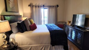 A neatly arranged bedroom with a bed, a television, a lamp, and a cabinet. - Johnny's Sedona Getaway - 2 Primary Suites 2 Bath (Sedona)