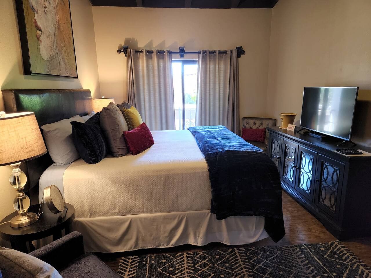A neatly arranged bedroom with a bed, a television, a lamp, and a cabinet.