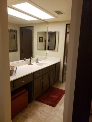 Un baño moderno con un espejo grande, un lavabo blanco y muebles oscuros.