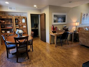 Un comedor con una mesa y sillas de madera, una cocina con estufa y armarios, y una sala de estar con sofá y lámpara.