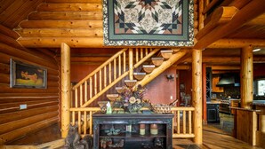 A wooden interior with a staircase, a fireplace, and a dining area. - Jewel of Escalante LLC (Escalante)
