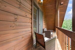 Ein Holzbalkon mit Korbmöbeln und Blick auf Grünflächen.