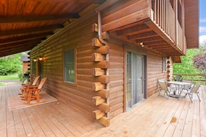 A log cabin with a deck, outdoor seating, and a covered patio area.