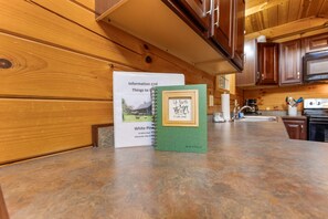 Una cocina de madera con una encimera, un libro de espiral titulado 'Up North A Cabin Journal' y un cartel blanco con 'Información y actividades' y 'White Pine 35 White Road Nelsonville, Ohio 4'.