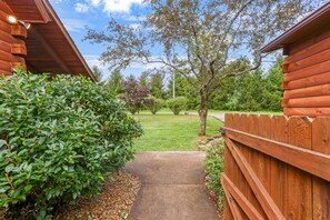 A wooden cabin with a concrete pathway leading to a grassy yard. - White Pine - Cozy Cabin with Relaxing Hot Tub! (Nelsonville)