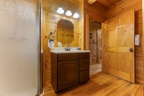A wooden cabin-style bathroom with a wooden vanity, a mirror, and a sink.