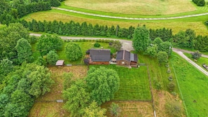 An aerial view of a rural property with a large house, a barn, and surrounding fields.