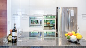 A modern kitchen with a stainless steel refrigerator, a glass island, and a fruit basket. - Villa between the jungle and the Caribbean Sea, Bahia Principe (Akumal)