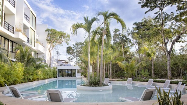 A modern pool area with lounge chairs and a wooden deck. - Villa between the jungle and the Caribbean Sea, Bahia Principe (Akumal)