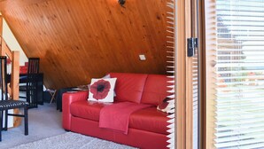 A red leather sofa with a red and white pillow, a wooden ceiling, and a window with blinds. - 2 bedroom accommodation in Kingsdown, near Deal (Kingsdown, near Deal)
