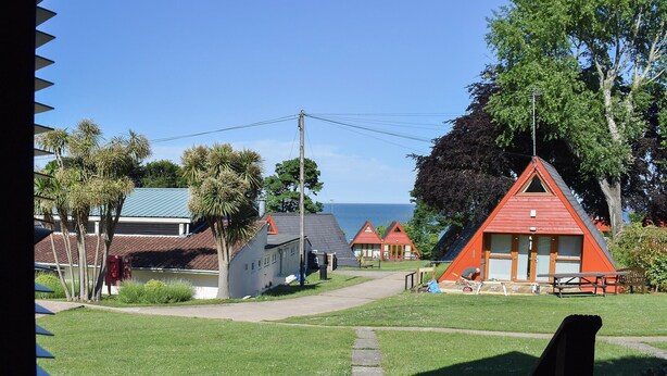 A coastal area with several red-roofed cabins, a grassy pathway, and a view of the sea. - 2 bedroom accommodation in Kingsdown, near Deal (Kingsdown, near Deal)