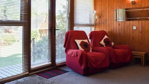 A room with two red chairs, wooden walls, and large windows with blinds. - 2 bedroom accommodation in Kingsdown, near Deal (Kingsdown, near Deal)