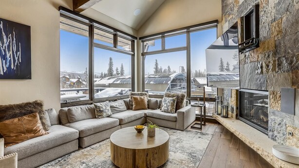 A spacious living room with a large sectional sofa, a round coffee table, and a fireplace.