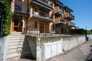 A multi-story residential building with balconies, a concrete retaining wall, and a staircase leading to the entrance. - N034 - Numana, large apartment with terrace (Sirolo)