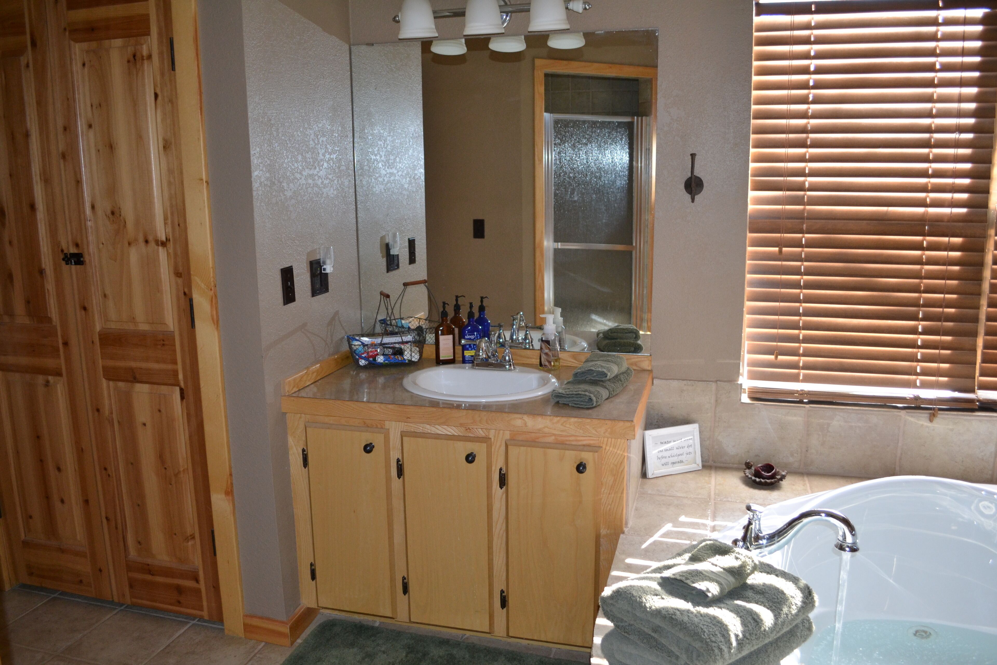 A bathroom with wooden cabinets, a sink, a mirror, and a bathtub.