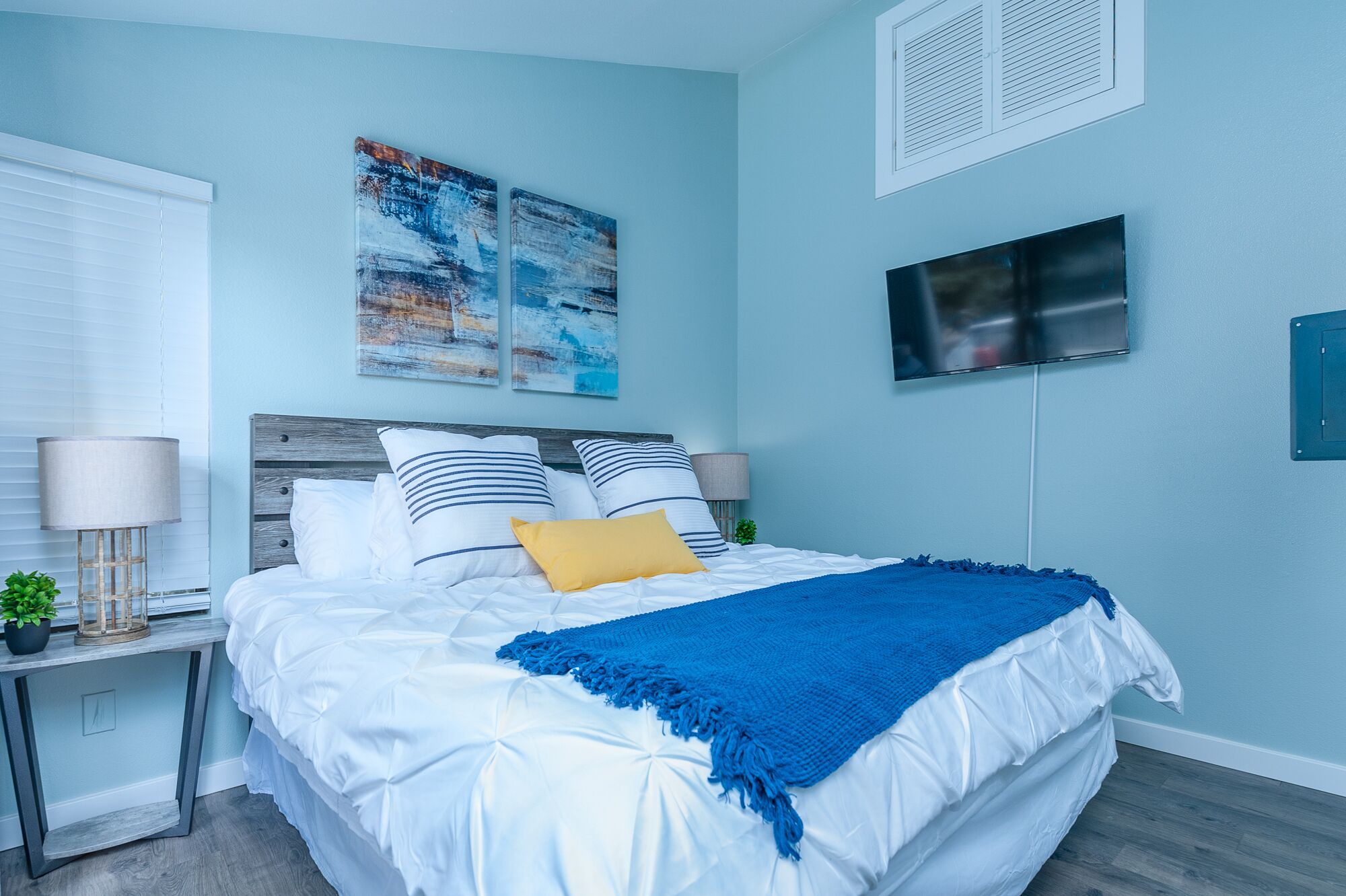 A bedroom with a bed, a TV, and artwork on the wall.