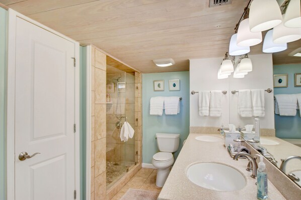 A bathroom with a shower, toilet, and two sinks.