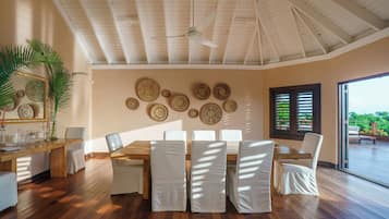 A dining area with a wooden table, white chairs, and a ceiling fan.