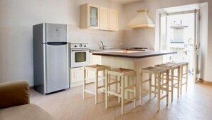 A modern kitchen with a refrigerator, oven, and bar stools. - S125 - Sirolo, new three-room apartment in the heart of the town (Sirolo)