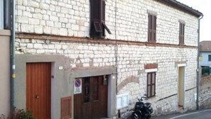 A stone building with a wooden door, a motorcycle parked outside, and a no parking sign. - S125 - Sirolo, new three-room apartment in the heart of the town (Sirolo)