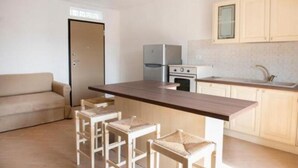 A compact kitchen with a central island, bar stools, a refrigerator, and a stove. - S125 - Sirolo, new three-room apartment in the heart of the town (Sirolo)