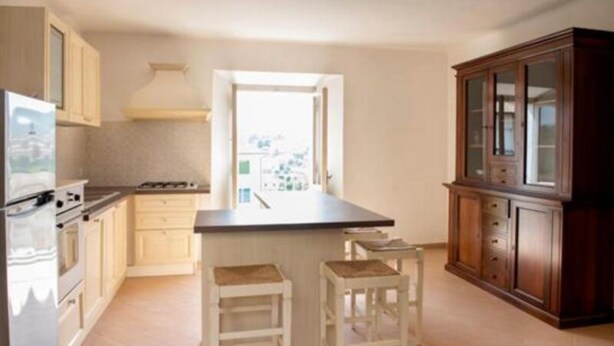 A kitchen with a stove, oven, and bar stools. - S125 - Sirolo, new three-room apartment in the heart of the town (Sirolo)