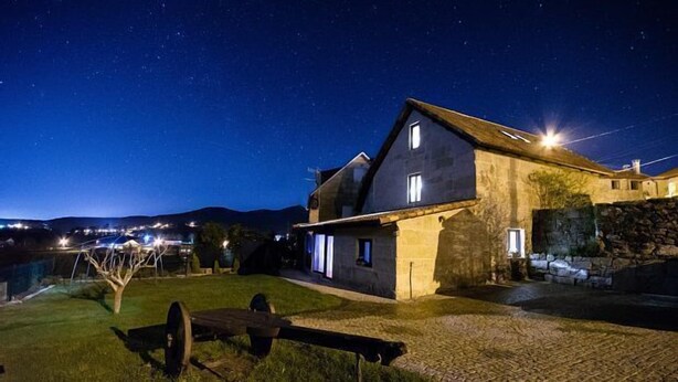 A stone house with a sloped roof and a small porch, surrounded by a grassy area and a cobblestone path. - Full rental house for 8-10 people, ideal for families with pets. (Ponte-Caldelas)