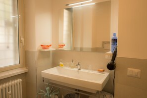 Bathroom features a sink, mirror, and hairdryer, with a window and radiator nearby.