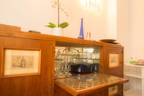 Um armário de madeira com bancada de vidro exibindo copos de vinho e um vaso azul.