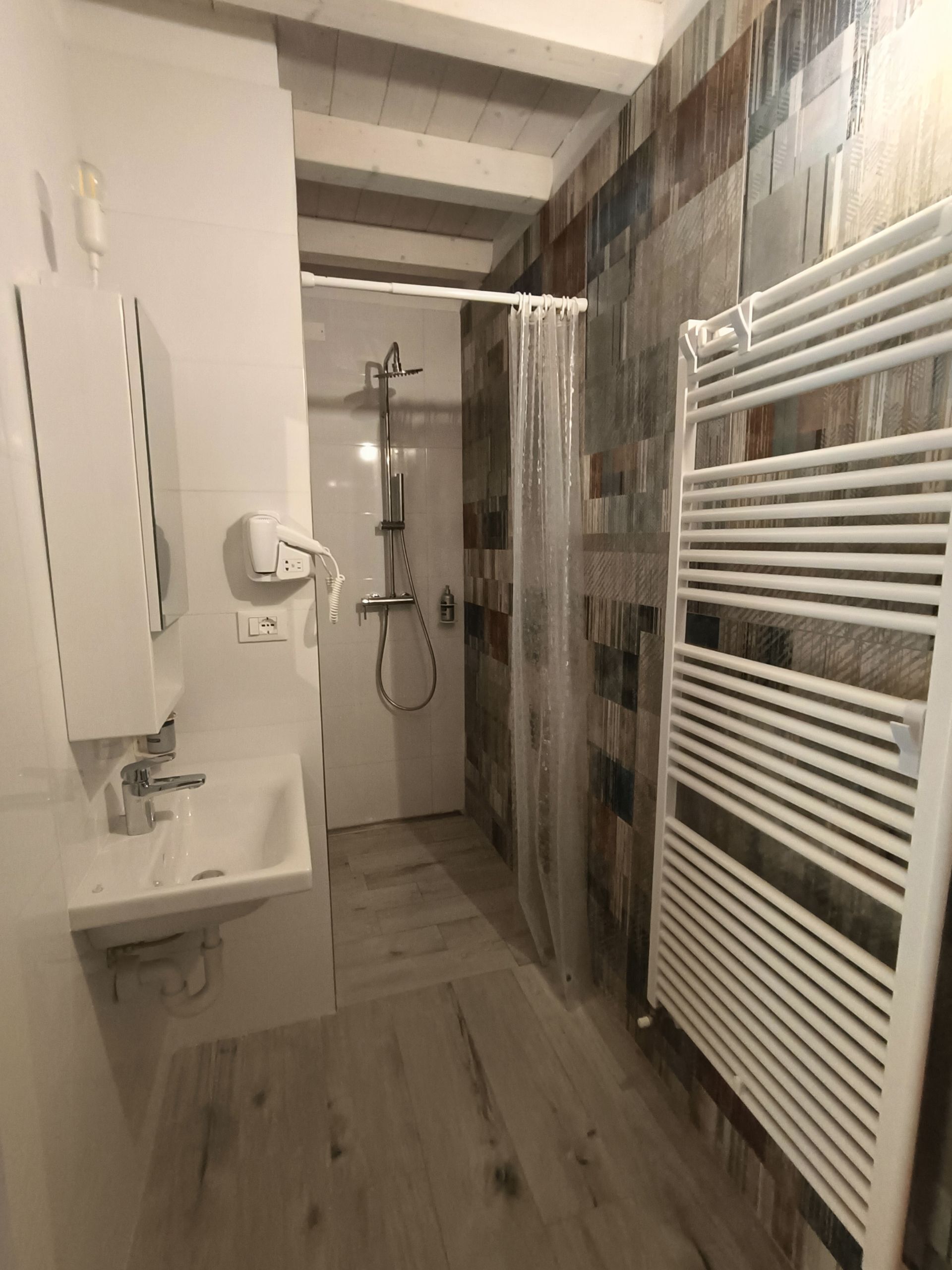 A modern bathroom with a shower, a sink, and a towel rack.