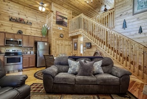 Relax in this inviting living area with a modern kitchen, comfortable sofa, and wooden staircase.