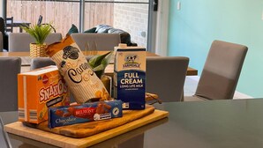 A table with snacks and milk in a room with a view of the outdoors.