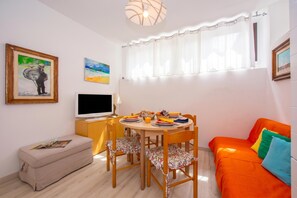 A living room with a dining table, chairs, a sofa, a TV, and artwork on the walls. - Casa Angerin 1 - 100m from sea, Alassio, Italy (Alassio)
