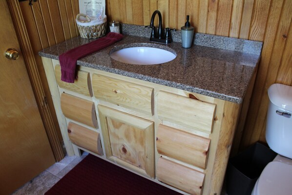 A wooden vanity with a granite countertop, a white sink, and a black faucet. - SLEEPS 16, 7 bedroom 4 baths w/ 2 game rooms, SXS rentals w/direct trail access (Atlanta)