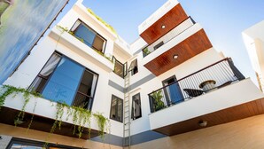 A modern multi-story building with large windows, a wooden facade, and a visible balcony. - Seaweed Luxury Villa&Spa (Da Nang)