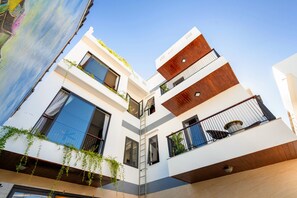 A modern multi-story building with large windows, a wooden facade, and a visible balcony.