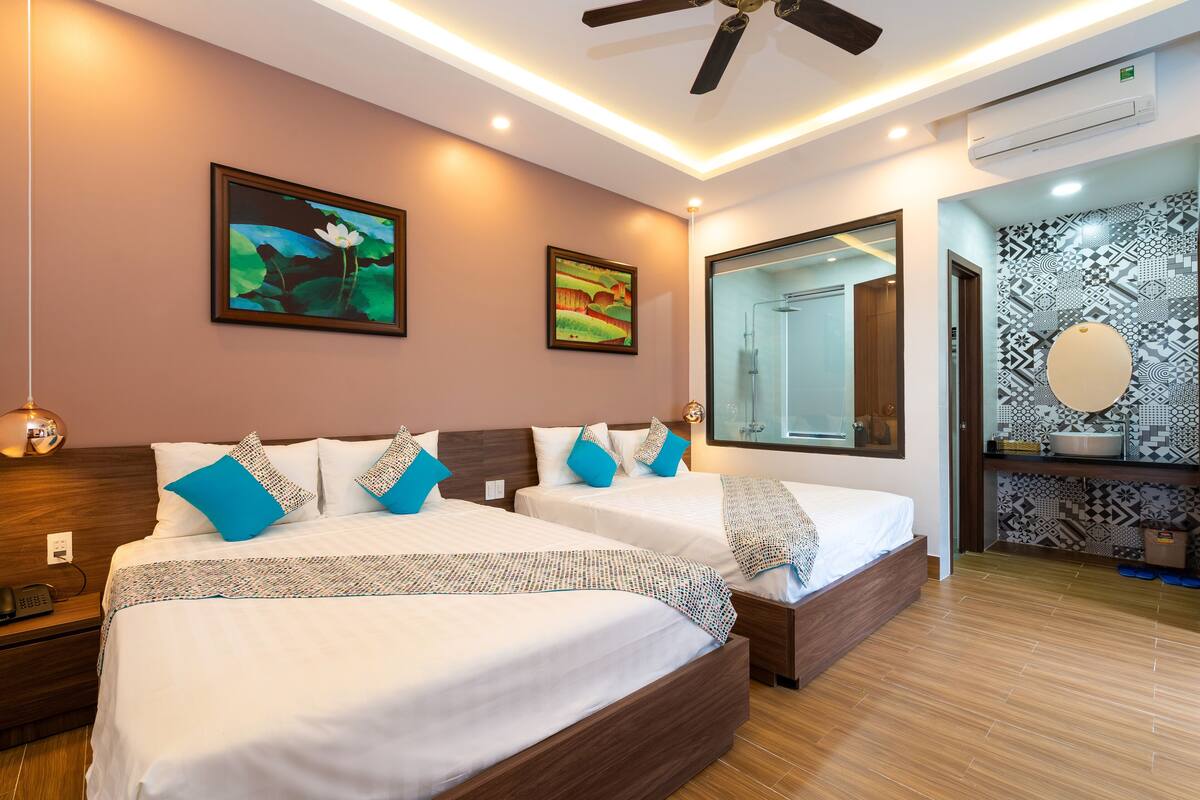 A hotel room with two beds, a ceiling fan, a large mirror, and a patterned wall.