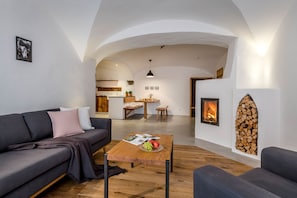 Ein modernes Wohnzimmer mit einer Couch, einem Couchtisch mit Früchten, einem Kamin und einer gewölbten Decke.