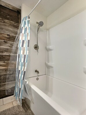 Tina con regadera, toallas, papel de baño